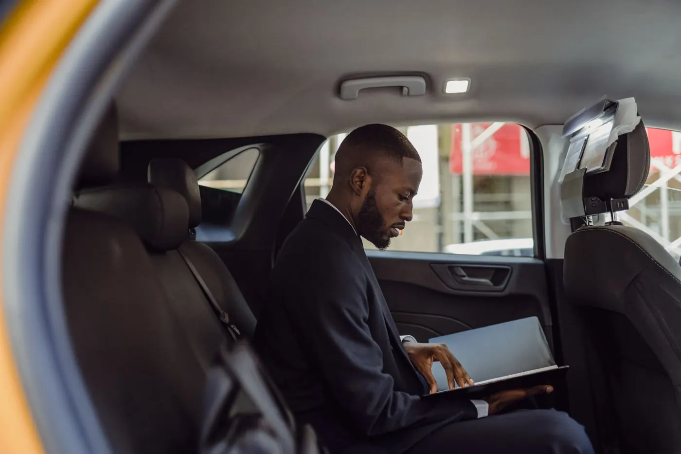 Passager travaillant sur son ordinateur à l'arrière d'un véhicule avec chauffeur